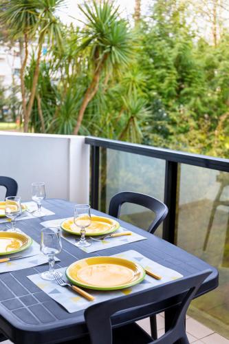 une table bleue avec des assiettes jaunes et des verres à vin dans l'établissement Les pieds dans le sable de la Plage Benoît - T2, à La Baule