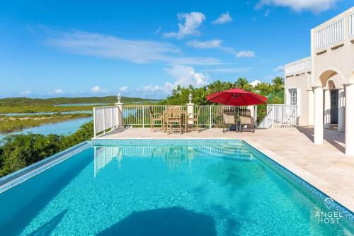 a swimming pool with a table and an umbrella at Breathtaking Chalk Sound Private Pool Sunset Villa in Providenciales