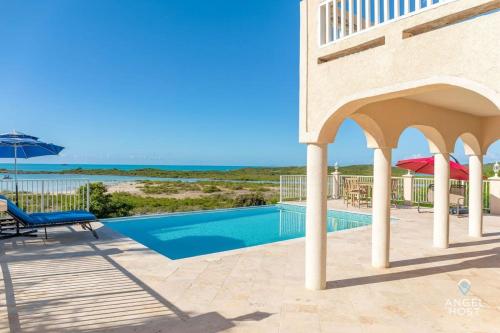 a villa with a swimming pool and an umbrella at Breathtaking Chalk Sound Private Pool Sunset Villa in Providenciales