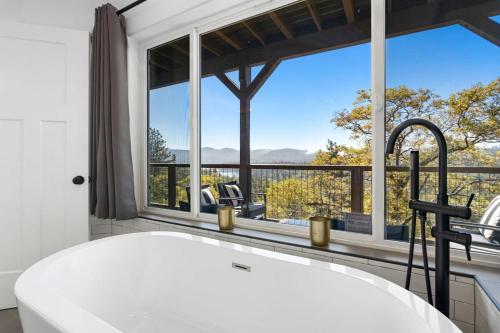 y baño con bañera y ventana grande. en Luxury Lakeview Home 2 Masters 3 Decks AC EV Charger Dogs eBikes, en Lake Arrowhead