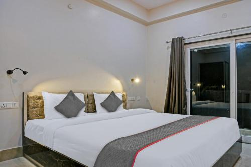 a bedroom with a large white bed and a window at Super Townhouse 1935 Hotel Navneeta Grand in Kakarmatha