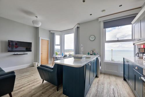 uma cozinha com armários azuis e vista para o oceano em Bay View Holiday Apartments em Scarborough
