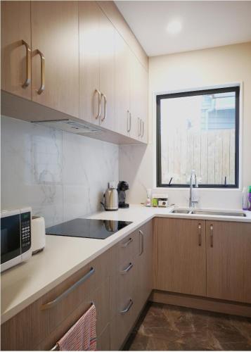 a kitchen with wooden cabinets and a sink and a window at W&M Orchid House in Auckland