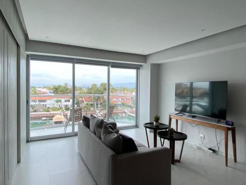 a living room with a couch and a large window at NEW Nautico with Marina View and Rooftop Pool plus Gym in Puerto Vallarta
