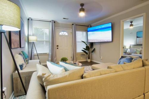 a living room with a couch and a flat screen tv at Bungalow Bliss ※ Beach Cottage Blocks From Ocean in Myrtle Beach
