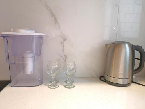 a coffee maker and two wine glasses on a counter at W&M Orchid House in Auckland