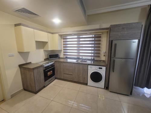 a kitchen with a refrigerator and a sink and a dishwasher at Gardens Company in Amman
