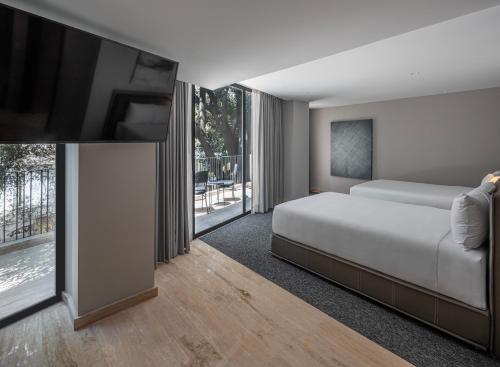 Un dormitorio con una cama y un televisor de pantalla plana. en Hotel Elements by Marquis, en Ciudad de México