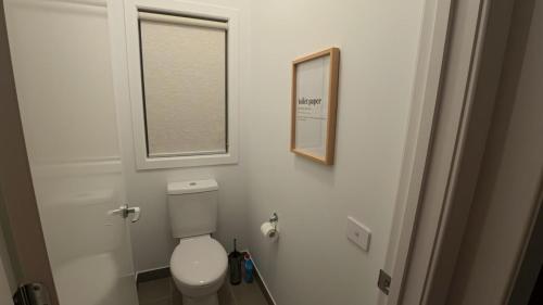 a white bathroom with a toilet and a window at Brand New House in Lakes Entrance in Lakes Entrance