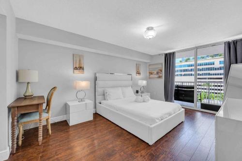 een witte slaapkamer met een bed, een bureau en een raam bij Beautiful 1 BED 1 BTH • Brickell in Miami