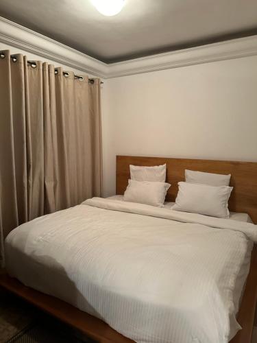 a bedroom with a bed with white sheets and pillows at two flat in Douala
