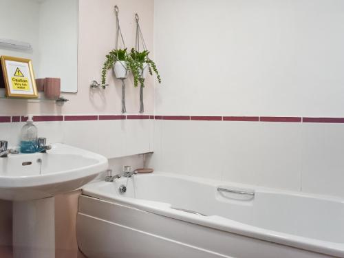 een badkamer met een wit bad, een wastafel en een bad tubermott bij Sycamore Cottage in Broomhill