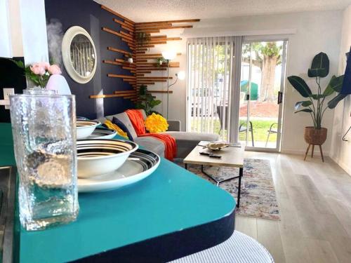 a living room with a blue table with plates on it at The Botanical Retreat, King Comfort & Poolside Peace in Gainesville