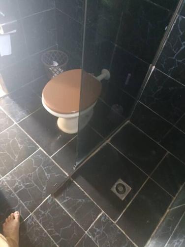uma casa de banho com WC e piso em azulejo em Linda Kit Net Mobiliada Individual em Dourados