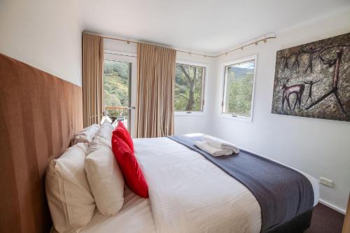 a bedroom with a bed with red and white pillows at Lhotsky Apartments in Thredbo