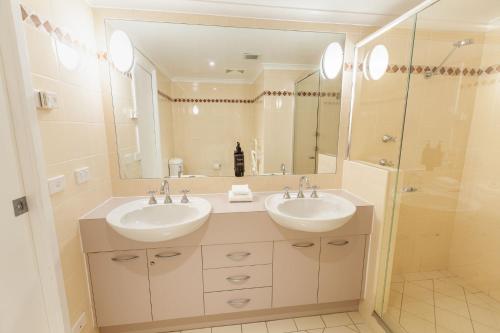 a bathroom with two sinks and a large mirror at Lhotsky Apartments in Thredbo