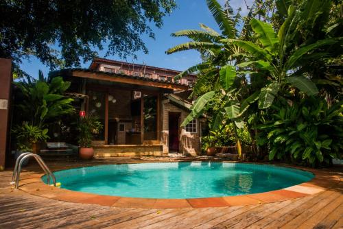 a swimming pool in front of a house at alua pousada ventos de camburi in Camburi