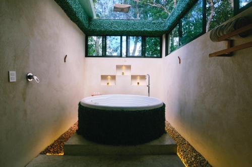 a bathroom with a large tub in a room with windows at Villas Zamna - Jungle Villas in Cozumel