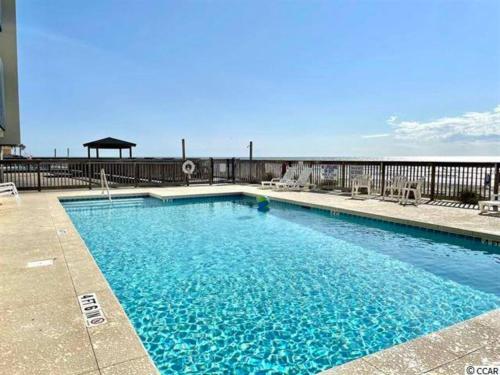 a swimming pool on a balcony with the ocean in the background at Ocean Breeze Beachfront Condo, Newly Renovated in Myrtle Beach