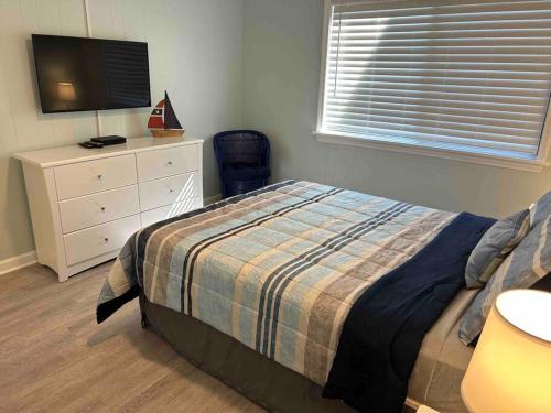 a bedroom with a bed and a dresser with a television at Ocean Breeze Beachfront Condo, Newly Renovated in Myrtle Beach