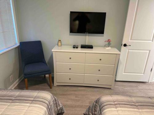 a bedroom with a dresser with a tv and a blue chair at Ocean Breeze Beachfront Condo, Newly Renovated in Myrtle Beach