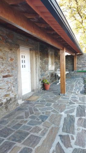 a stone patio with a white door and a building at O Recanto do Sobreiro in Vale de Porco