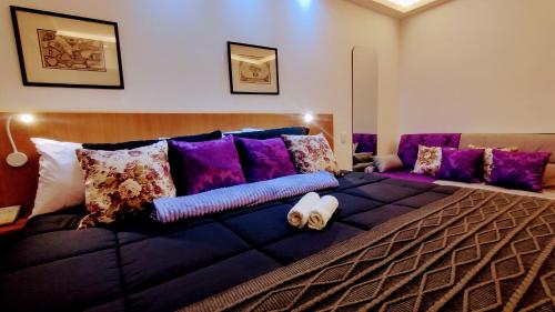 a large bed with purple pillows on it at Hotel M-RCURE Av Paulista GRAND PLAZA - Master Deluxe king Studio Veranda - Executive Class - By LuXXoR in Sao Paulo