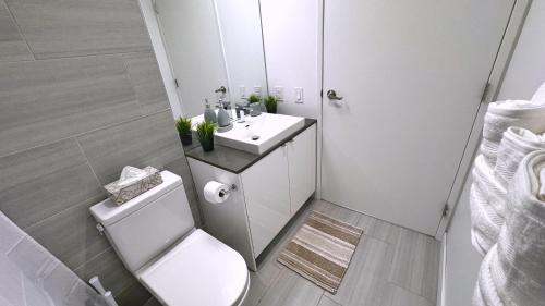 a white bathroom with a toilet and a sink at Cozy 1BR Apt - Downtown Winnipeg in Winnipeg