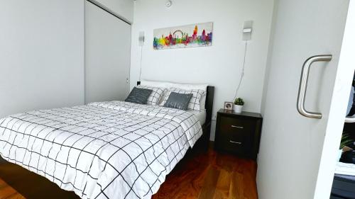 Cozy 1BR Apt - Downtown Winnipeg في وينيبيغ: غرفة نوم بيضاء مع سرير وموقف ليلي