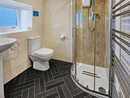 a bathroom with a toilet and a sink and a shower at Cart Cottage - 28343 in Staintondale