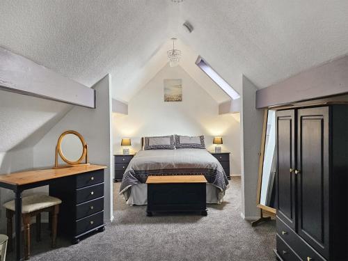a bedroom with a bed and a desk with a mirror at Stable Cottage - 29155 in Staintondale