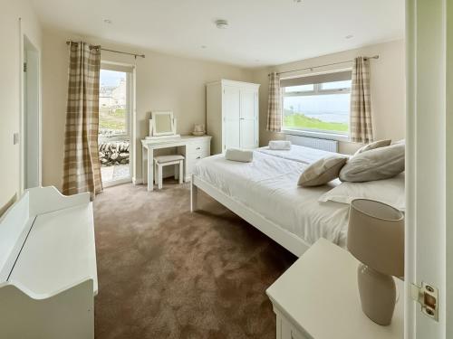 a bedroom with a large white bed and a window at High Auchenlarie Cottage in Carsluith