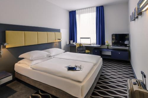 ein Hotelzimmer mit einem großen Bett und einem TV in der Unterkunft Mercure Hotel Frankfurt Eschborn Helfmann-Park in Eschborn