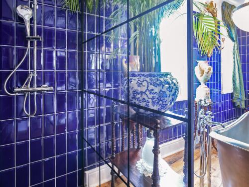 a blue tiled bathroom with a shower and a sink at St Marys Chambers in Mold