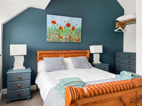 a bedroom with blue walls and a bed with red flowers at Holly Cottage in Ashover