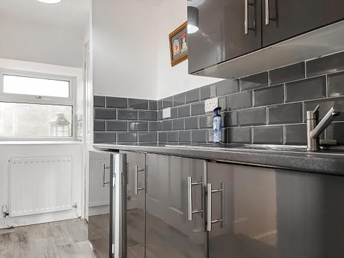 a kitchen with stainless steel cabinets and a sink at Holly Cottage in Ashover