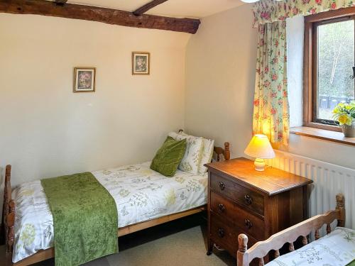 a bedroom with a bed and a dresser and a window at Millstone Cottage - Uk46676 in Highley
