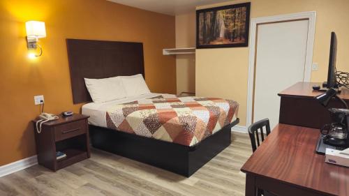 Habitación de hotel con cama, escritorio y TV. en Deep River Motel, en Deep River