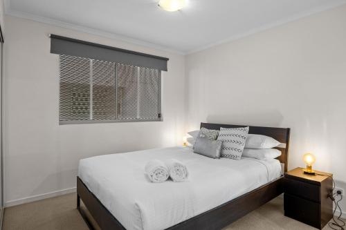 a white bedroom with a bed with white sheets and pillows at Urban Oasis in South Brisbane in Brisbane