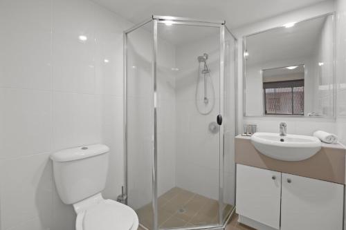 een badkamer met een douche, een toilet en een wastafel bij South Vale Apartments South Brisbane in Brisbane
