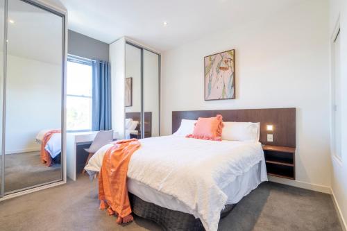 - une chambre avec un grand lit et un miroir dans l'établissement Heritage terrace with mod twist, à Hobart