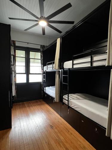 a room with two bunk beds and a ceiling fan at Howzit Hostels Hawaii in Hilo