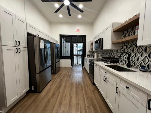 a kitchen with white cabinets and a black refrigerator at Howzit Hostels Hawaii in Hilo