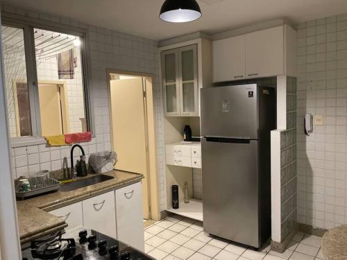 a kitchen with a stainless steel refrigerator and white cabinets at Apartamento Orla Praia do Canto in Vitória