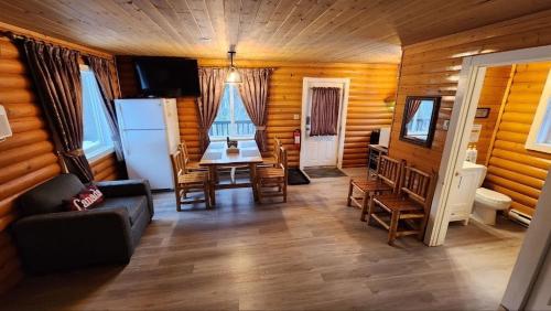a living room with a table and chairs and a refrigerator at Mt. Revelstoke Alpine Chalets in Revelstoke