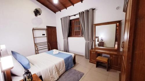 a bedroom with a bed and a desk and a mirror at Golden Shower Inn in Kandy