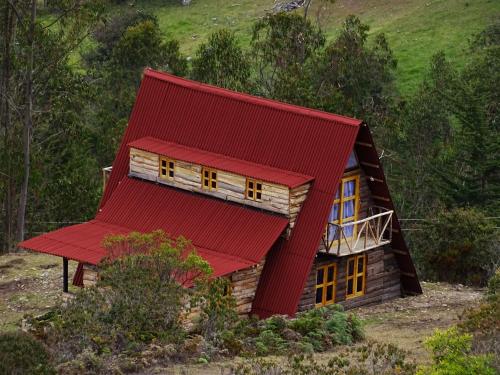 een kleine blokhut met een rood dak bij La Teja Experience in Güicán