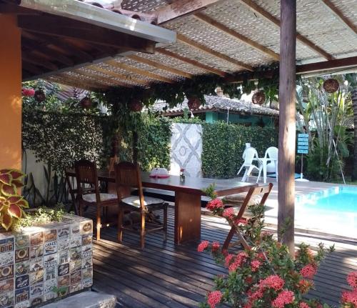 a patio with a table and chairs and a swimming pool at Ôxe Uai Hostel in Arraial d'Ajuda