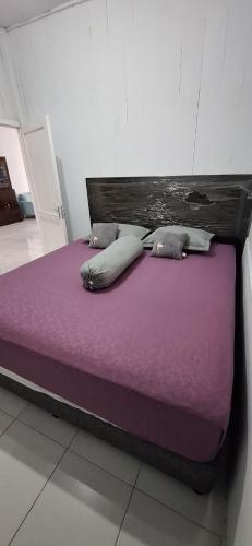 a bed with purple sheets and pillows in a room at Umah Bapak in Takengon
