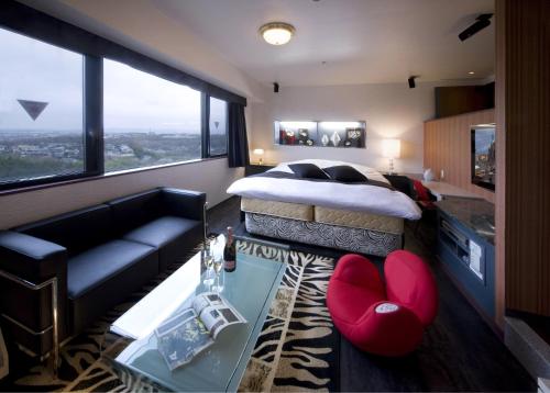ein Schlafzimmer mit einem Bett, einem Sofa und einem Tisch in der Unterkunft HOTEL & SPA ISLAND (Adult Only) in Toyota